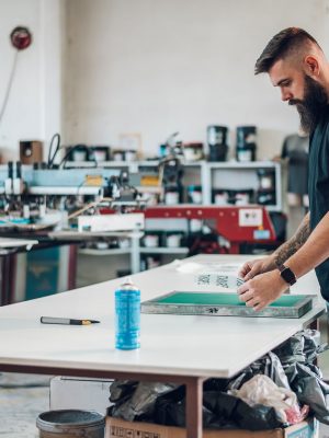 male-worker-preparing-screen-printing-film-in-work-QWCPTEXa